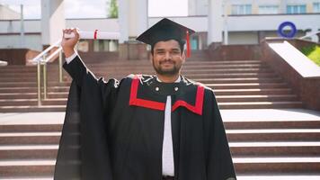 Indian student standing with diploma in university campus on his graduation day video