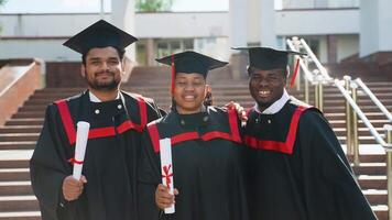 Young diversity group of students in graduation gown hugs in university campus video