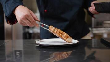 Chef puts finished beef steak from pan onto a plate in a restaurant kitchen video