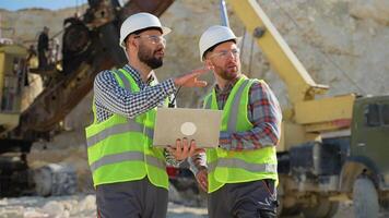 Construction workers engineers in uniform with laptop are talking at the quarry mining site video