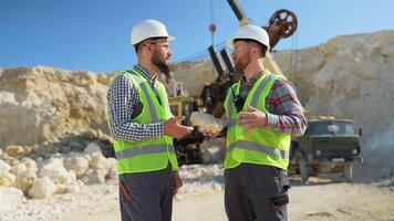 Two engineers geologists holds stone in hand and discussing quarry excavation plan video