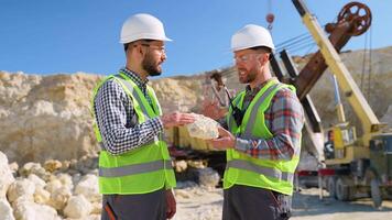 Two engineers geologists holds stone in hand and discussing quarry excavation plan video