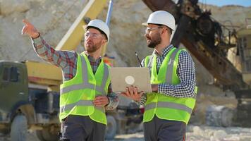 Two men workers in uniform with laptop are talking at the stone quarry video