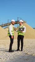 Construction workers engineers with laptop are talking at the quarry mining site. Vertical video