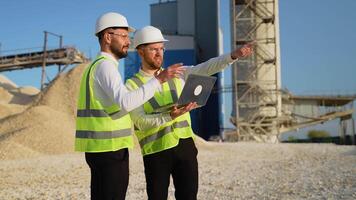 Construction workers engineers with laptop are talking at the quarry mining site video