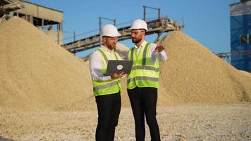 Two men workers with laptop talking in stone quarry video