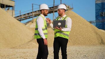 Construction workers engineers with laptop are talking at the quarry mining site video