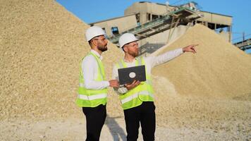 Two men engineers with laptop are talking at the stone quarry factory video