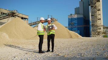Two men engineers with laptop are talking at the stone quarry factory video