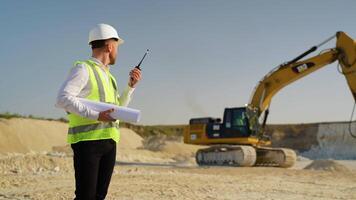 Foreman instructing worker in excavator drill machine using walkie talkie radio set at quarry video