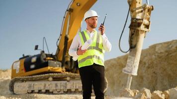 Foreman giving commands to employee in drilling machine using walkie talkie at stone quarry video