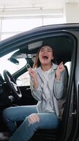 Happy woman customer is showing key of her new car, looking at camera and smiling. Vertical video