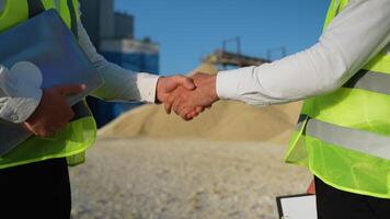 Two men engineers shaking hands at sand quarry video