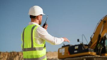 Foreman giving commands to employee in excavator using walkie talkie at construction site video