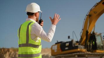 Foreman giving commands to employee in excavator using walkie talkie at construction site video