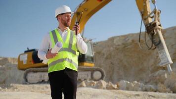 Engineer instructing worker in excavator drill machine using walkie talkie radio set at quarry video