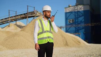 Foreman instructing workers using walkie talkie radio set at sand quarry video