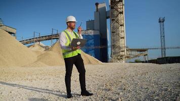 Foreman engineer with laptop instructing workers using walkie talkie radio set at quarry video