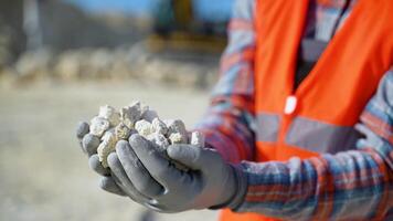Worker engineer hold gravel in hand, checks quality at quarry, close up video