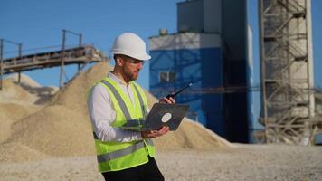 Foreman with laptop instructing workers using walkie talkie radio set at quarry video