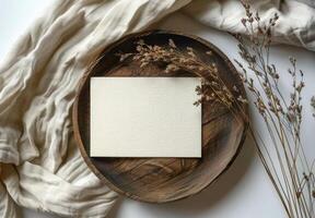 Blank White Card on Rustic Wooden Plate With Dried Grass on Cream Fabric photo