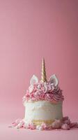 A delightful unicorn cake decorated with pink frosting and whimsical features on a pink background photo