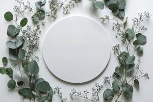 A simple wooden circle surrounded by delicate greenery on a white background photo