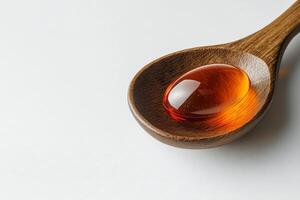 Wooden spoon filled with golden fish oil capsules on a neutral background in a minimalist setting photo