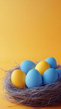 Brightly colored eggs in a natural nest on a vibrant yellow background during springtime photo