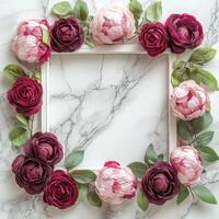 Decorative floral arrangement surrounding a blank frame on a marble tabletop photo
