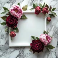 Decorative floral arrangement surrounding a blank frame on a marble tabletop photo