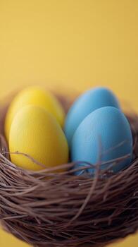 Brightly colored eggs in a natural nest on a vibrant yellow background during springtime photo