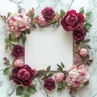 Decorative floral arrangement surrounding a blank frame on a marble tabletop photo