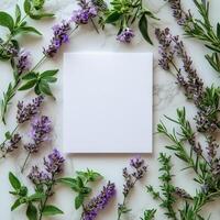 Hands holding a blank paper surrounded by lilac flowers on a light surface photo