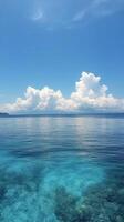 Clear blue water reflecting fluffy clouds over a calm ocean during a bright sunny day photo