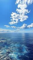 Clear blue water reflecting fluffy clouds over a calm ocean during a bright sunny day photo