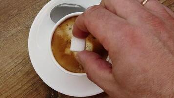 The man drops a cube of white sugar into the coffee and stirs it with a spoon video