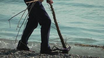 Man Walking on a Beach With a Stick video
