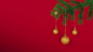 Golden Christmas balls appear and sparkle on the Christmas tree branch on a red background. New Year's card, banner, stop motion animation. Copy space video