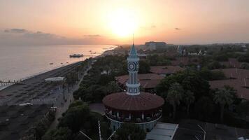 Drone Flight Over Clock Tower at Sunset with Beach, Mountain, and Sea Views video