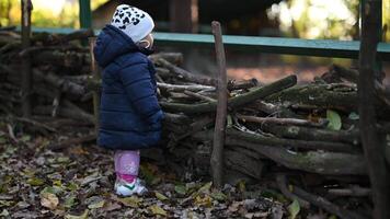 Cute Baby Girl Stands by Wooden Fence in Autumn and Looks Away in Slow Motion video