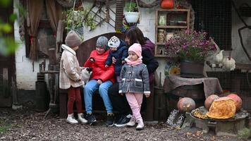 glücklich Familie mit Mutter und vier Kinder posieren im ein rustikal Landschaft mit Hühner und Kürbisse im Herbst video