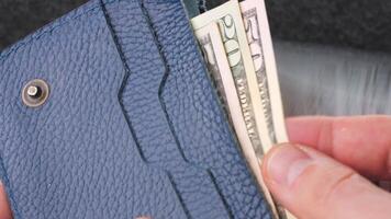 A closeup view of cash being stored in a blue wallet for financial purposes video