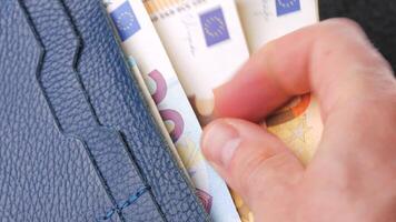 A closeup view of cash being stored in a blue wallet for financial purposes video