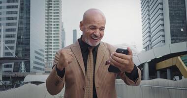Man on work break on street city watches game favorite team on smartphone. Face lights up with joy when team wins. Waving arms, manager screams with delight, noting importance of victory achieved. video