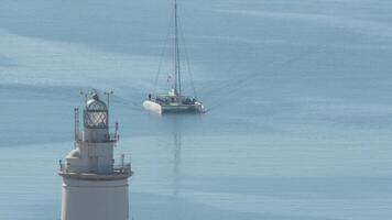 Catamaran entering port next to the lighthouse on a sunny day video