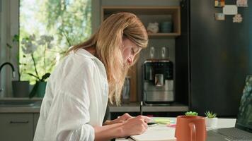 Person is sketching in notebook while working remotely at desk with laptop. Freelance work at home office. Graphic designer drawing sketch video