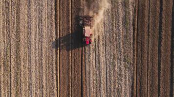 Red tractor working in agricultural field, cultivating and plowing dry soil, aerial view. Agribusiness concept. Small farming concept video