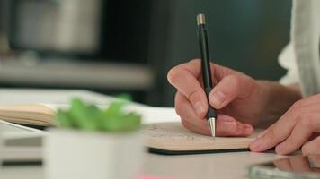 Person is sketching in notebook while working remotely at desk with laptop. Freelance work at home office. Graphic designer drawing sketch video