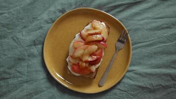 Yammy toasts with various peaches and fruits and cream-cheese on a gray background. top view video